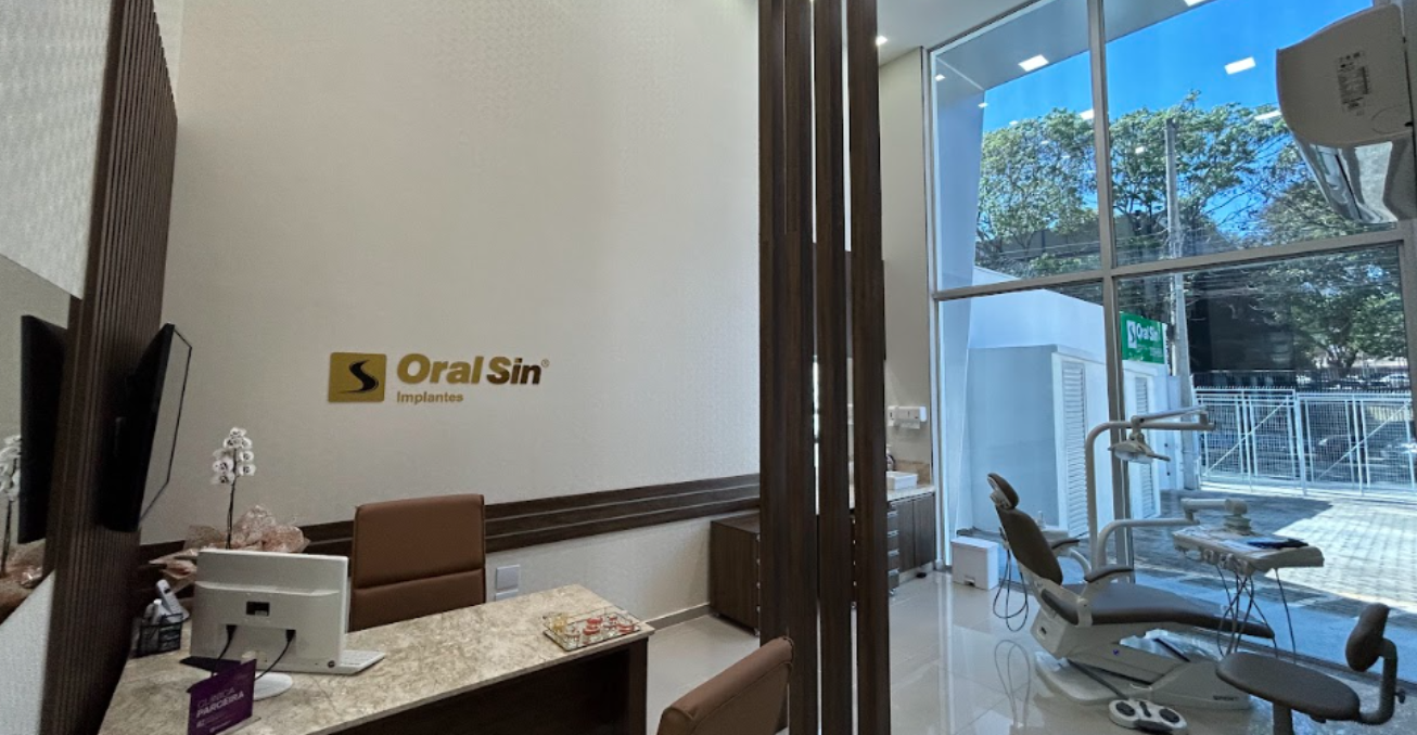 Consultório com cadeira odontológica moderna e janela com vista para a rua.